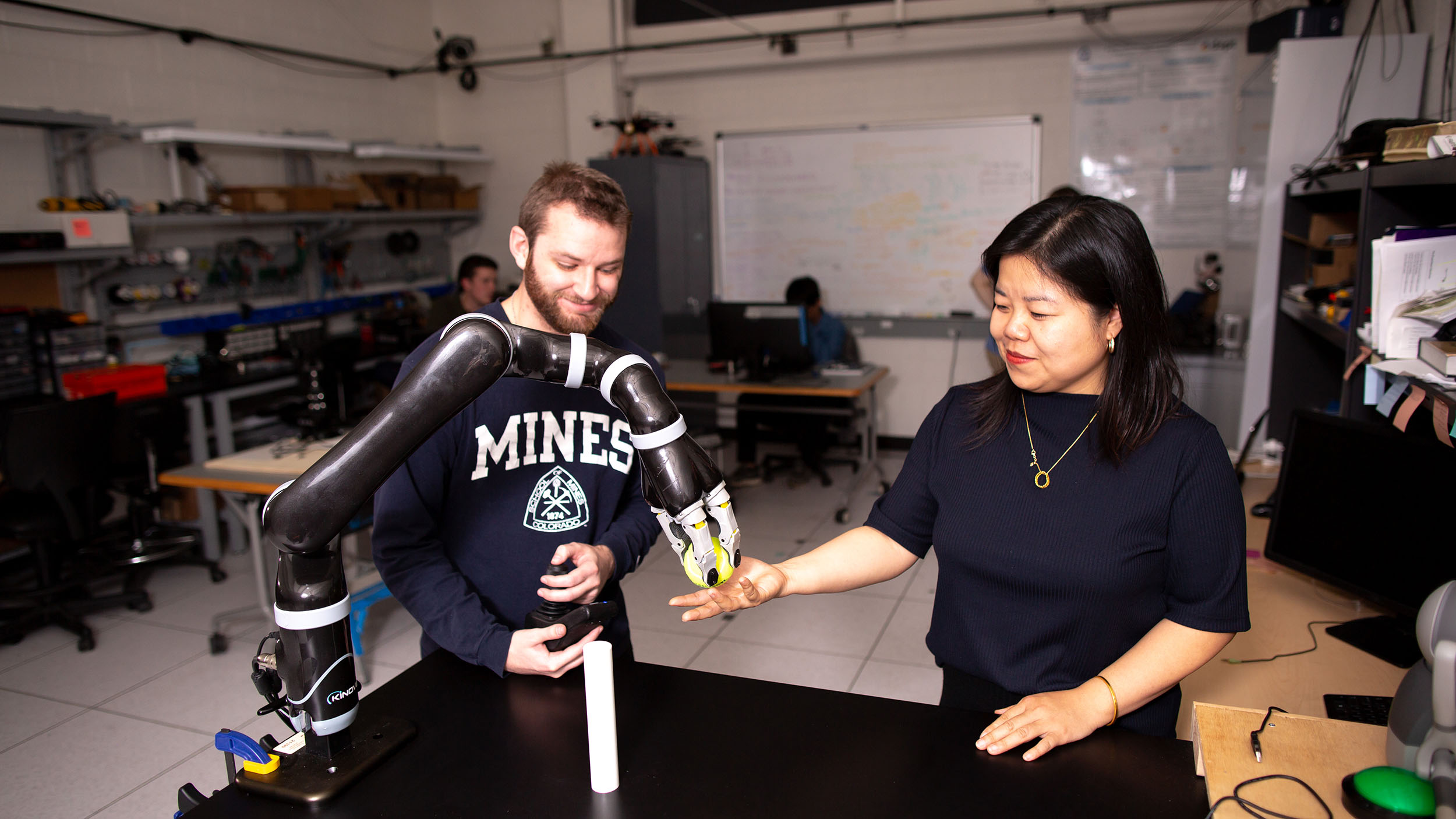 A man and a woman standing next to a table with a robot.