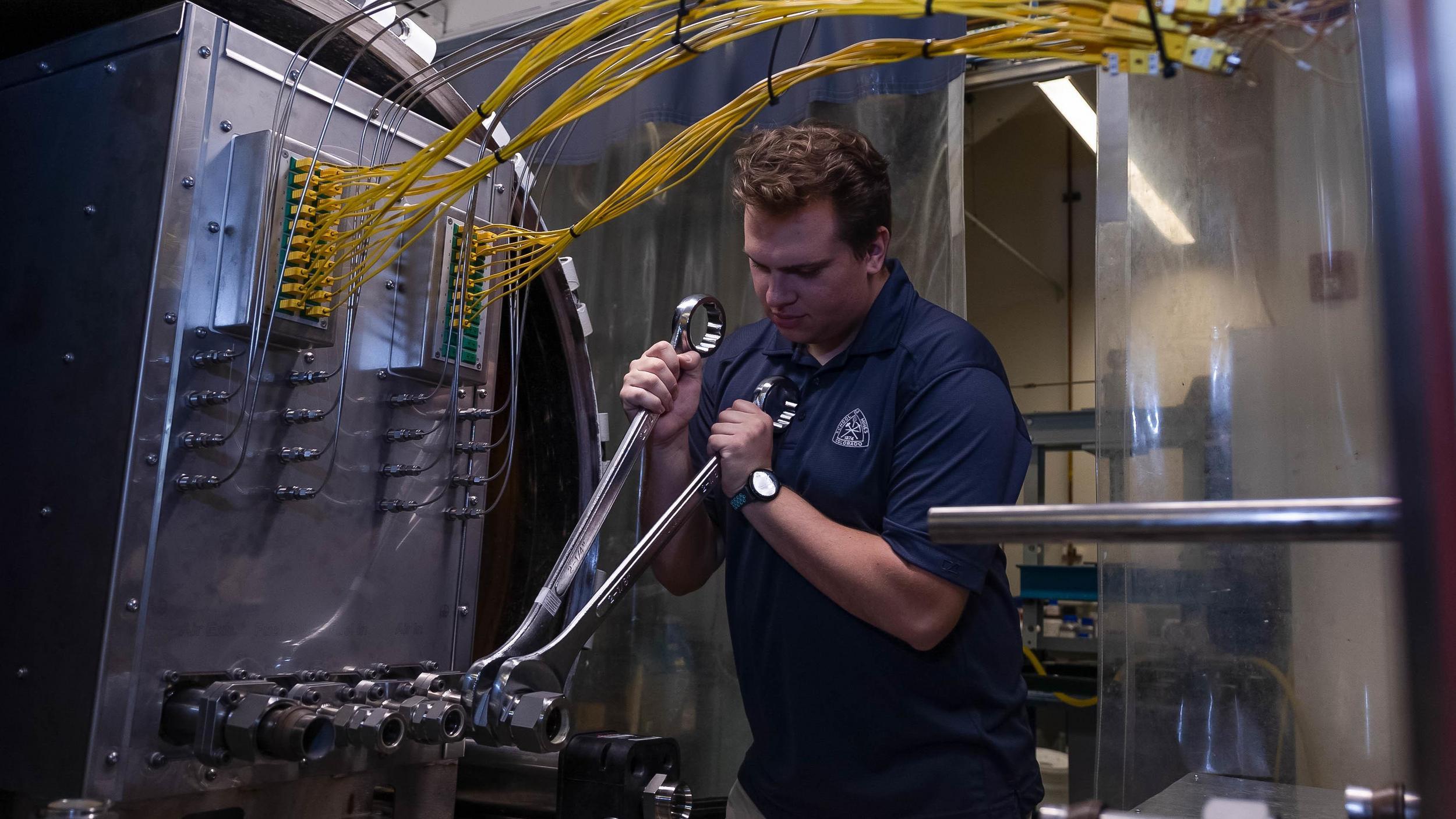 A man in a blue shirt is working on a machine.