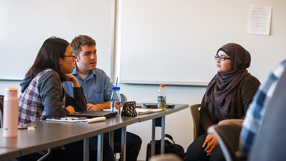 A group of people sitting around a table in a classroom.