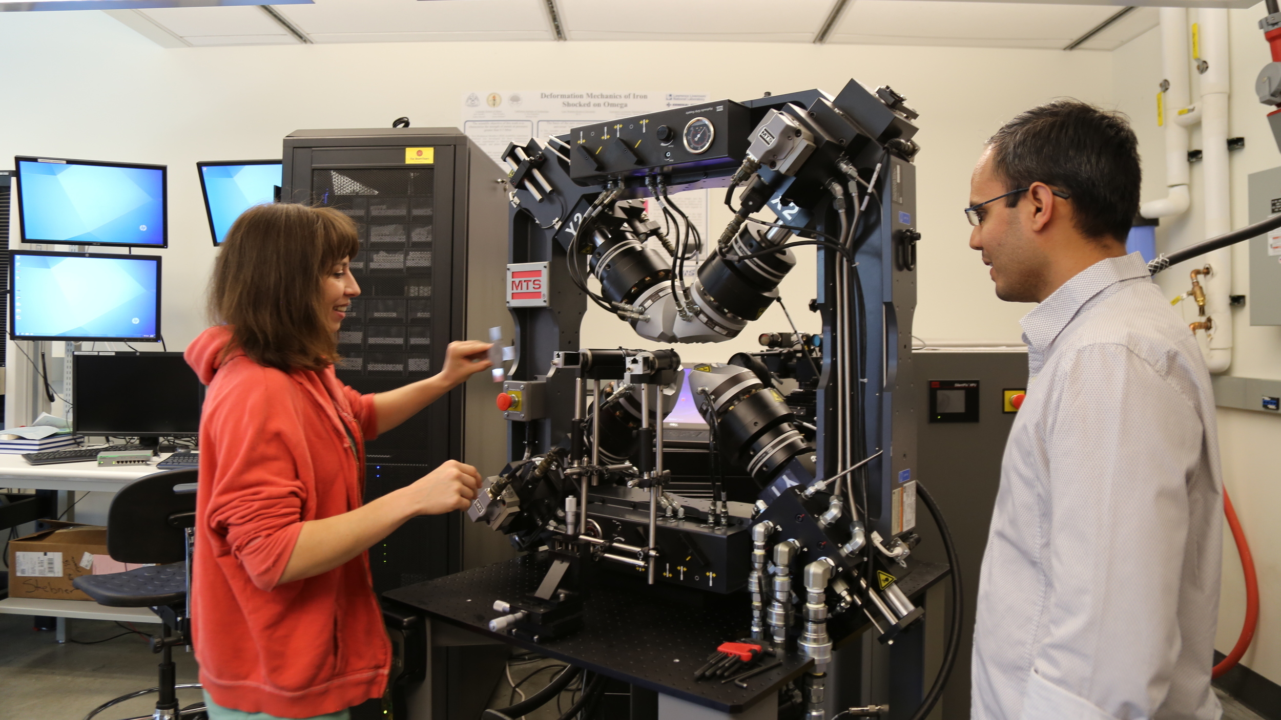 A man and a woman looking at a machine in a lab.