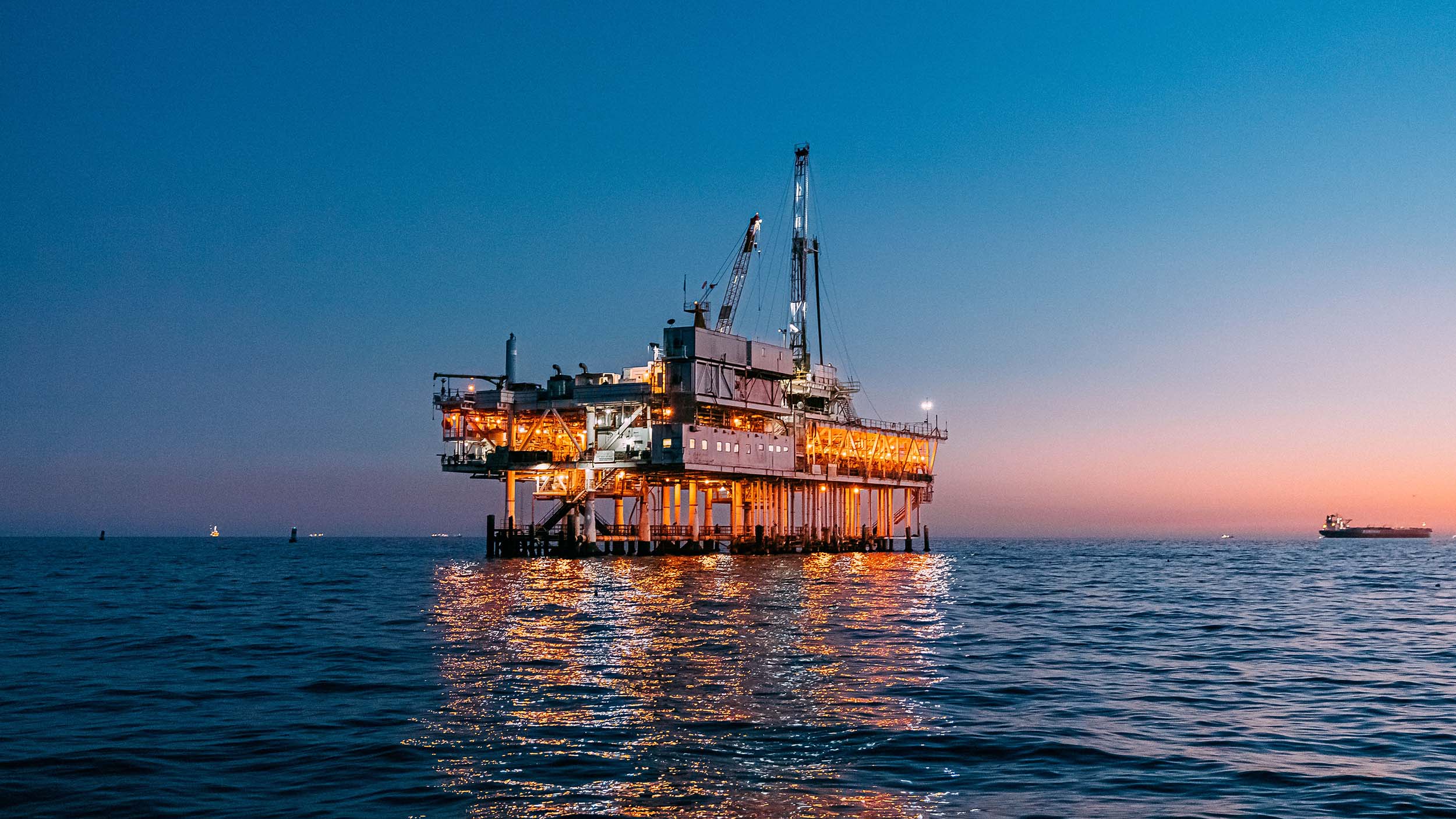 An oil rig in the middle of the ocean at dusk.
